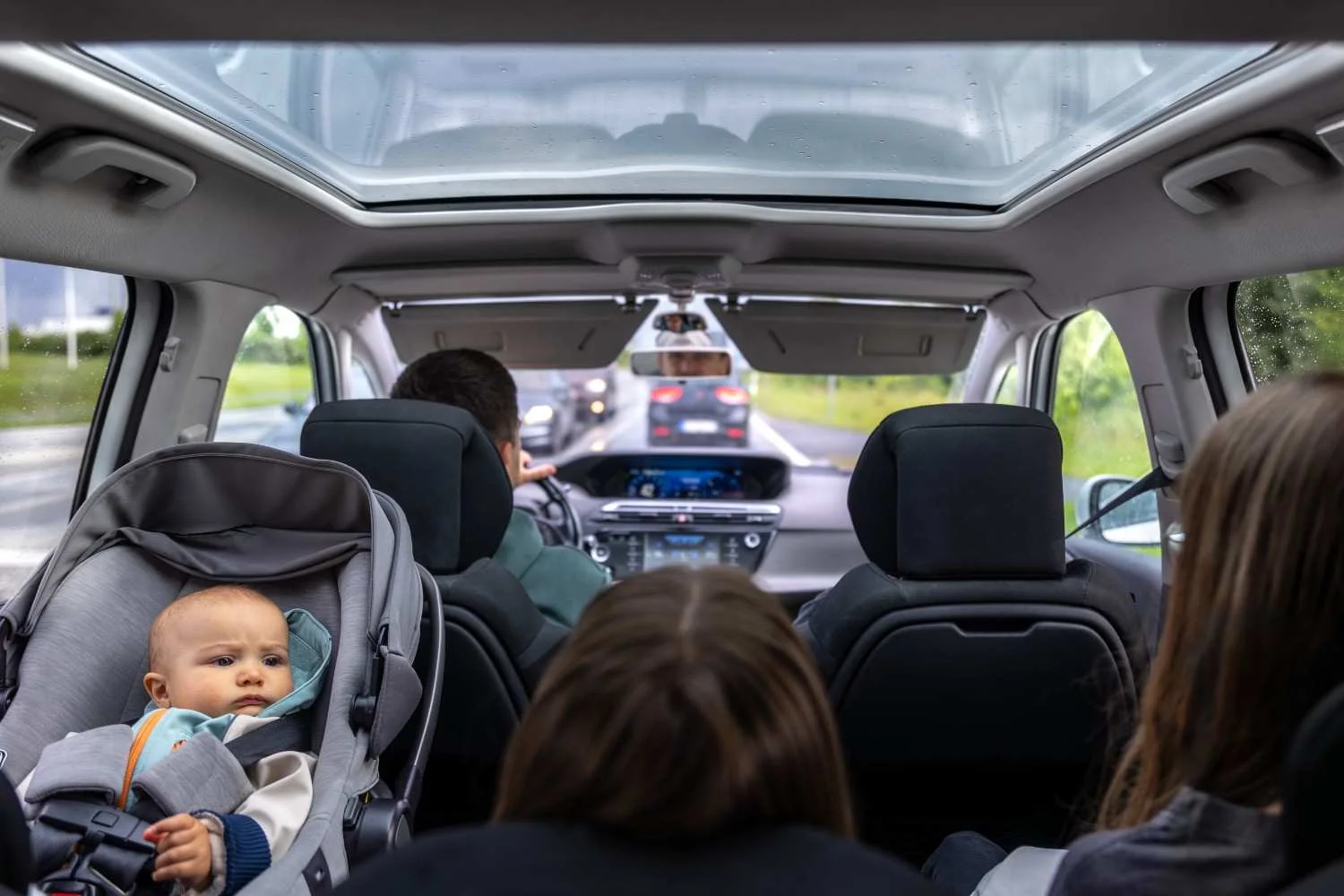 Family riding together in a car with a baby in a rear seat